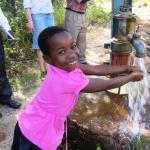 A young girl practices hand washing in Zimbabwe. 