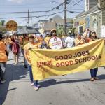 March behind a banner that says:  Good Jobs Good Schools