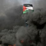 waving Palestinian flag in midst of black smoke