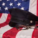 USA flag with cop hat and handcuffs