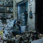 photo of workers in a room piled high with bags of discarded electronic waste.