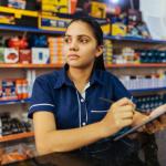 photo of a woman with a clipboard in front of grocery shelves  