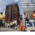 men in hardhats in front of a building in some states of being built