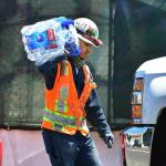 Worker carrying a block of ice to a truck.