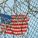 USA flag seen through barbed wire