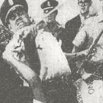 Uniformed police officer wrestles a U.S. flag from a 5-year-old picketer
