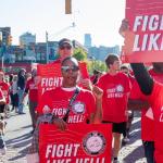 Photo of people marching in red tees and holding signs that say fight like hell 