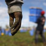 photo of a worker walking highlighting their rough and soiled hand.