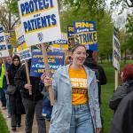 photo of a line of workers with signs such as Protect Our Patients.