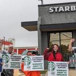 A few Starbucks customers and union allies stand in front of a Starbucks store with signs saying they support Starbucks workers. ta m  