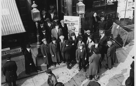 Photo of men in suits and coats standing in front of the union building. 