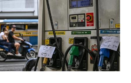 Photo of a gas pump with a sign "out of stock" on a busy street. 