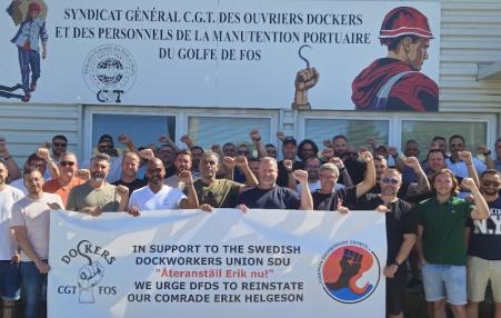 Photo of a group of French dockworkers with raised fists and a banner in support of a Swedish dockworker  
