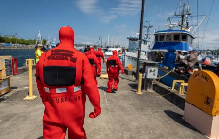 Photo of the backs of suited safety worker walking along a dock.