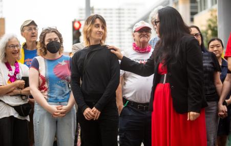 Photo of people standing behind a speaker at a press conference. 
