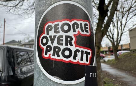 Photo of a sign on a post that says PEOPLE OVER PROFIT