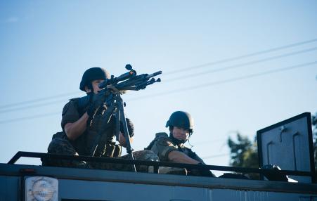 A police sniper atop a Special Weapons and Tactical vehicle.