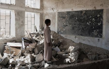 A Yemeni student stands in the ruins of his former classroom. 