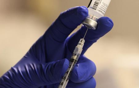 A pharmacist fills a syringe to prepare a dose of vaccine for front-line health care workers in Torrance, CA. 