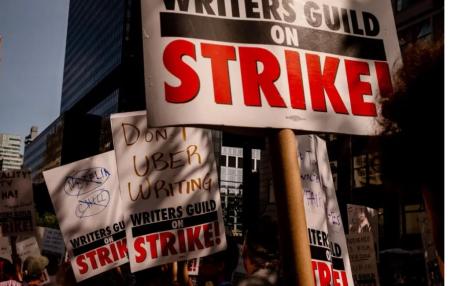 Placards reading writers guild on strike being help by picketers. 