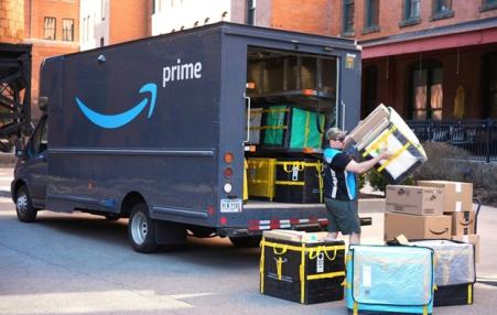 Photo of an Amazon truck getting loaded in the back end by workers. 