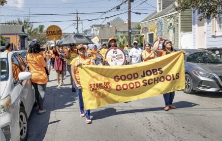 March behind a banner that says:  Good Jobs Good Schools