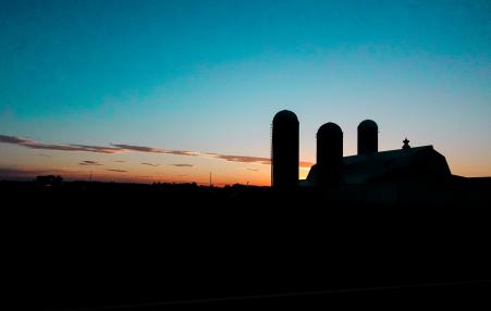 Silos in the foreground against the horizon of the setting sun.