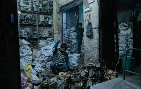 photo of workers in a room piled high with bags of discarded electronic waste. 
