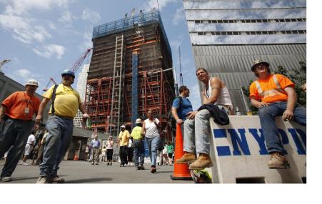 men in hardhats in front of a building in some states of being built