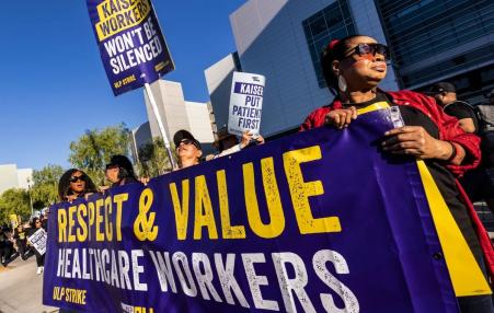 Photo of workers rallying holding a sign that says: Respect & Value Healthcare Workers