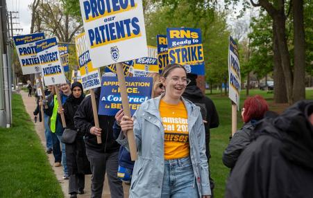 photo of a line of workers with signs such as Protect Our Patients.