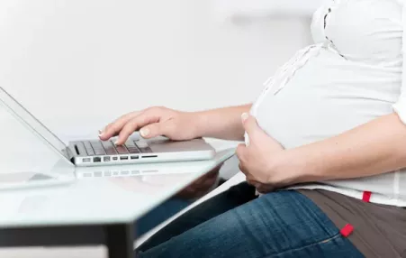 photo of the torso of a pregnant women a desk. 