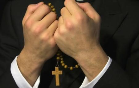 photo of the hands of a priest with a rosary  