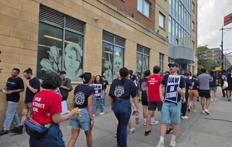 Photo of people on a picket line with signs that say UAW on strike