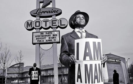 Photo of man in the foreground holding a sign that says, I AM A MAN 