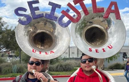 photo of two workers with tubas side-by-side with the acronyms of the two unions  :  SEIU and UTLA